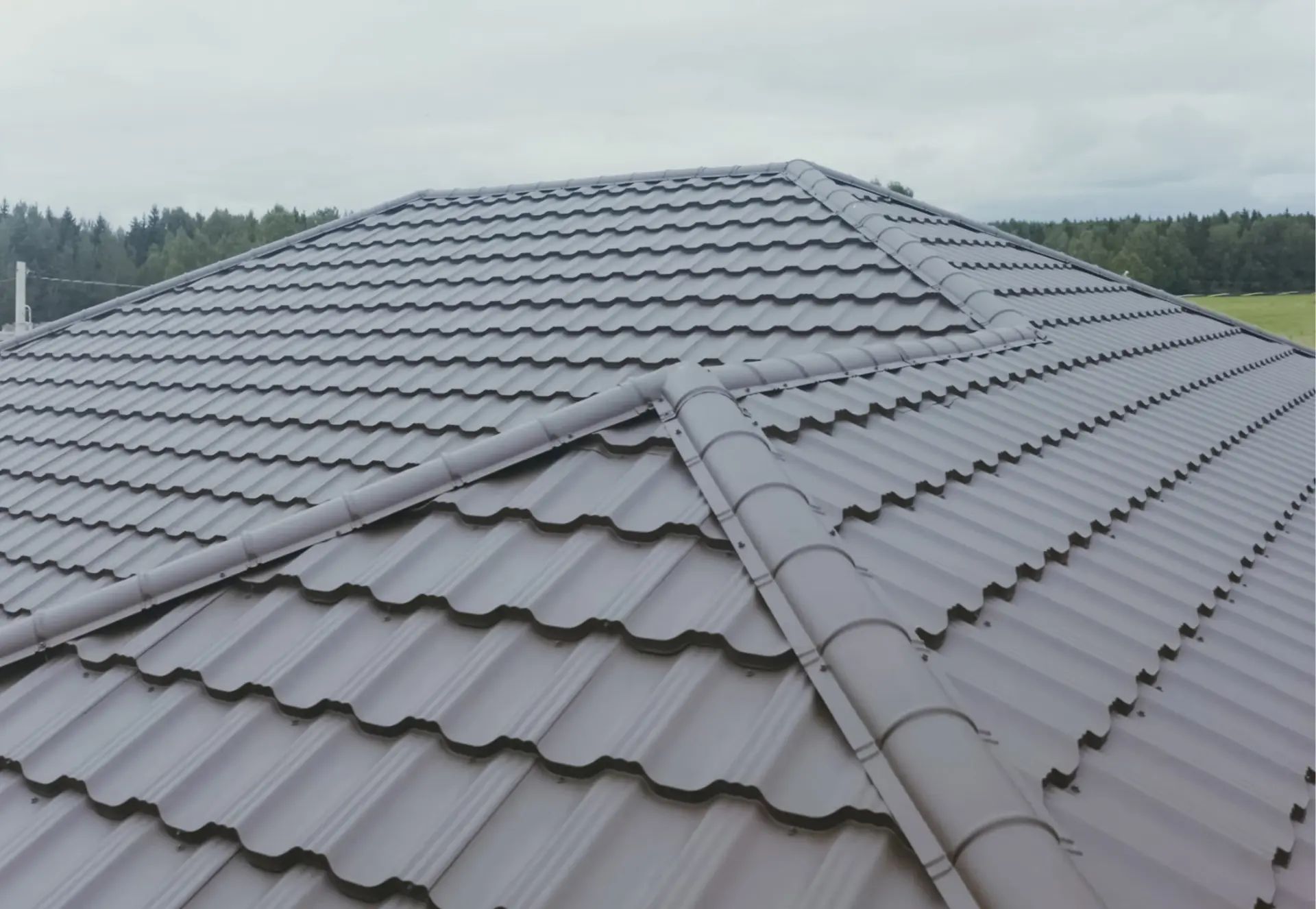 Gros plan sur des tuiles de toit métalliques gris foncé avec un design d'emboîtement précis